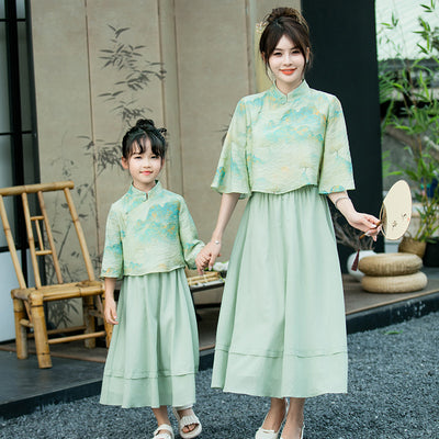 Mother and daughter in matching light green Chinese style cheongsam suits with patterned tops and solid skirts. - Image 4