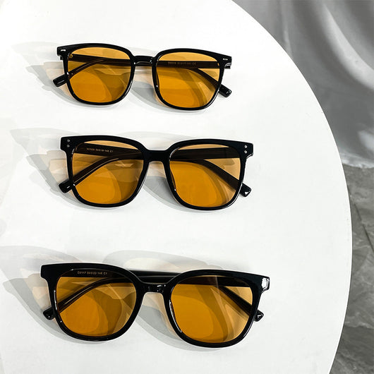 Black full-frame sunglasses with brown lenses, featuring a boxy style and visible dimensions.