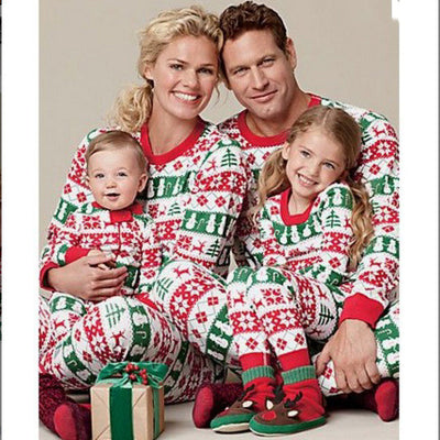 Family of four wearing matching red, green, and white Fair Isle Christmas pajamas, smiling together.