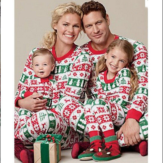 Family of four wearing matching red, green, and white Fair Isle Christmas pajamas, smiling together.