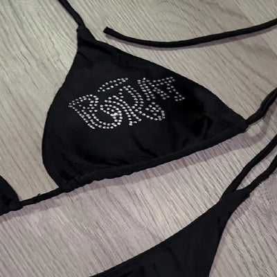 Black halter bikini with rhinestone 'BRAT' lettering on triangle top and tie-side bottom, displayed on white faux fur. - Image 3