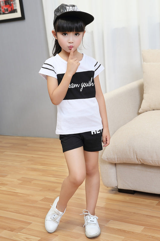 Young girl in a white short-sleeve t-shirt with a black stripe and black shorts, wearing a black cap. - Image 8