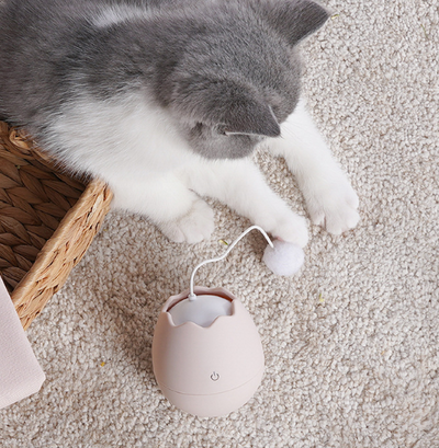 White egg-shaped automatic cat toy with a yellow interior and a flexible wire holding a yellow fuzzy ball. - Image 5