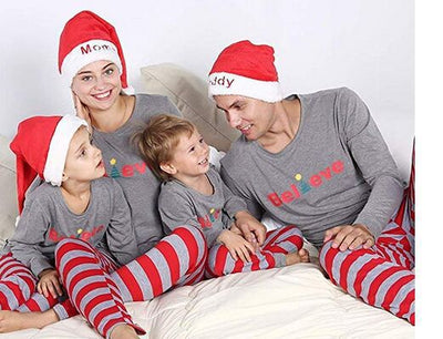 Family of four in matching grey long-sleeve tops and red striped pants, posing in a festive holiday setting. - Image 7