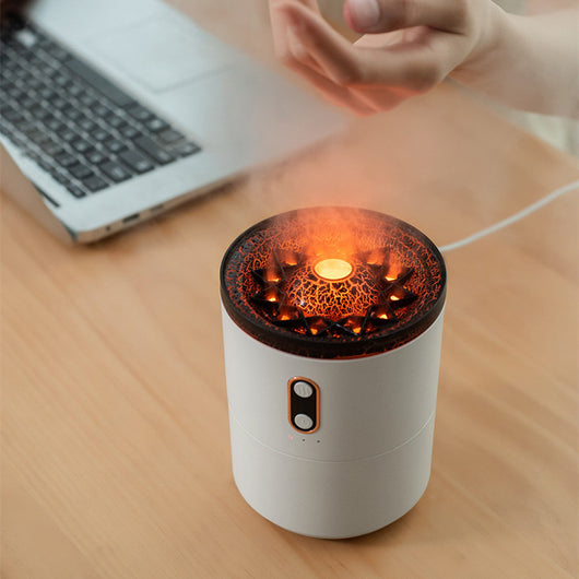 White volcanic flame aroma essential oil diffuser emitting orange light and mist on a wooden desk next to a laptop. - Image 2