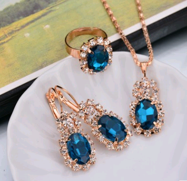 Rose gold-toned necklace, earrings, and ring set with large oval clear gemstones surrounded by smaller stones. - Image 7