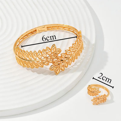 Gold wheat ear leaf cuff bracelet and matching open ring set on a white textured surface. - Image 4