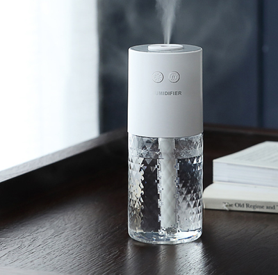 Dark blue and clear portable humidifier with a textured water tank on a white desk next to a laptop. - Image 6