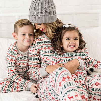 Family of four wearing matching white, red, and green fair isle Christmas pajamas with reindeer and snowflake patterns. - Image 4