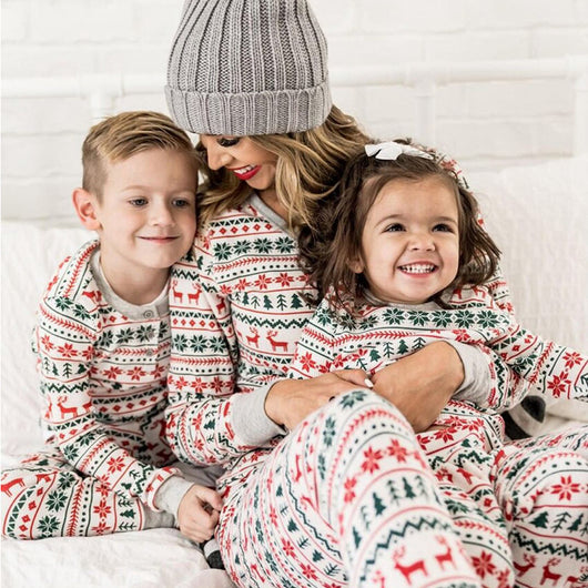 Family of four wearing matching white, red, and green fair isle Christmas pajamas with reindeer and snowflake patterns. - Image 4