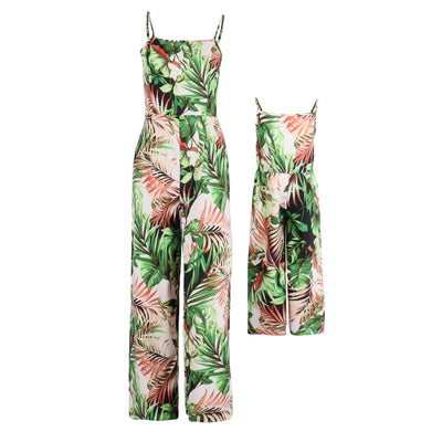 Mother and two daughters in matching green tropical print jumpsuits, posing outdoors in a sunny resort setting. - Image 4