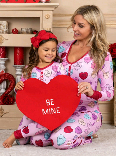 Pink long-sleeve pajama set with a conversation heart print, red Henley neckline, and matching full-length pants.