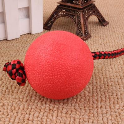 Red rubber dog ball with a red and black braided rope, featuring a knotted loop, on a light brown carpet. - Image 2