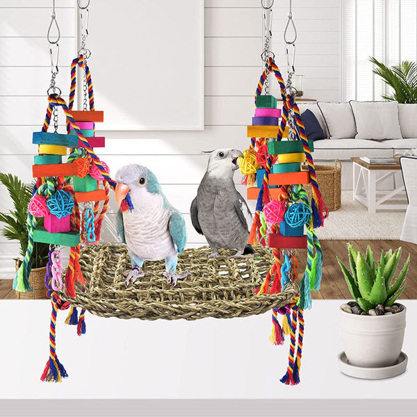 Colorful parrot toy with a woven grass hammock, hanging ropes, wooden blocks, and woven balls, with two parrots.