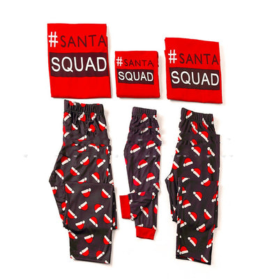 Matching family Christmas pajamas with red long-sleeve tops reading "#SANTA SQUAD" and black pants with a red Santa hat pattern. - Image 5