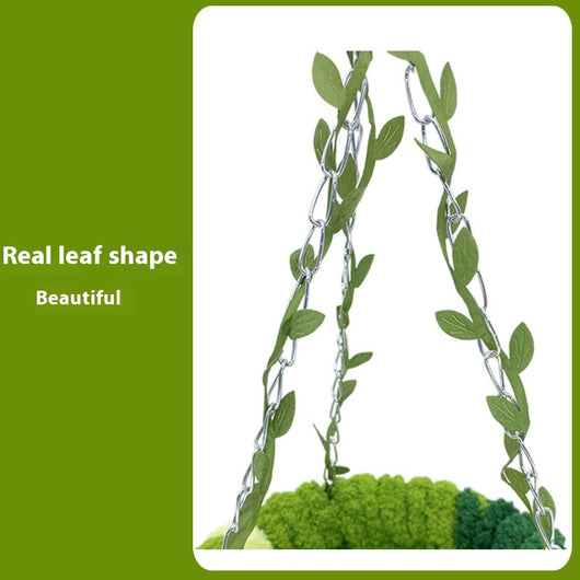 Small forest style plush bird hammock in green and yellow, hanging from a chain with artificial leaves. - Image 3
