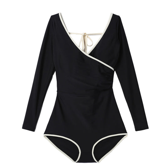 Woman wearing a black long-sleeve one-piece swimsuit with a wrap-style V-neck and light cream trim. - Image 5