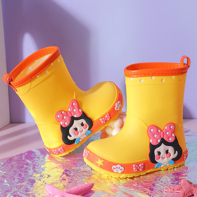 Bright yellow children's rain boots with a green cartoon dinosaur design and orange trim, held by hands. - Image 7