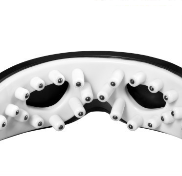 White and black eye massager with a goggle-like design, featuring a white frame and dark lenses, on a wooden surface. - Image 4