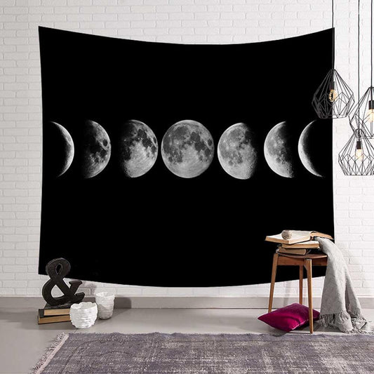 Black tapestry featuring a horizontal display of the moon's phases, from crescent to full and back, against a white brick wall.