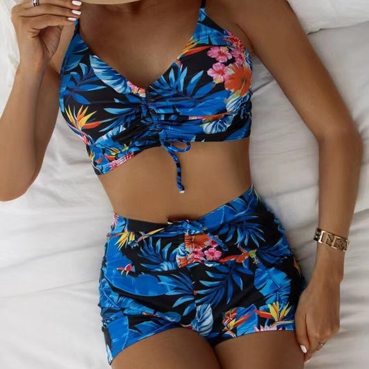 Blue two-piece swimsuit with white floral print, featuring a ruched crop top and matching boxer shorts. - Image 2