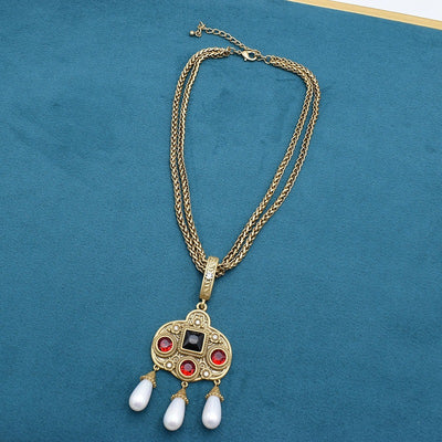 Vintage gold-toned necklace with double chain, ornate pendant featuring red and black glass inlays, and three white pearl tassels. - Image 5