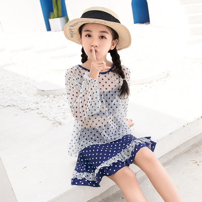 Woman in a cute and sweet three-piece swimsuit with a sheer white polka dot long-sleeve top and navy blue polka dot swim skirt. - Image 11