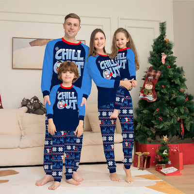 Woman wearing a navy blue and light blue Christmas pajama set with a "CHILL OUT" snowman graphic and fair isle patterned pants.