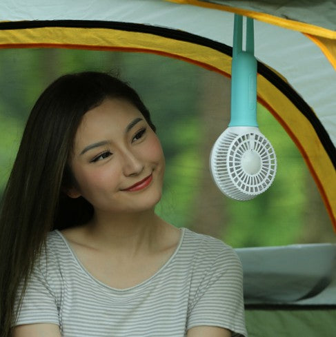 Lime green and white mini USB portable fan with a flexible strap, lying on a light wooden surface. - Image 3