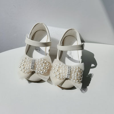 Beige girls' princess shoes with pearl and rhinestone bows, featuring a flat heel and a convenient Velcro strap. - Image 3