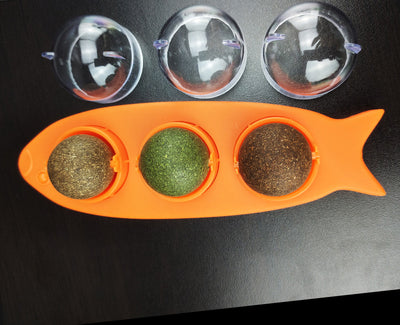 Pink fish-shaped cat molar stick toy with three compartments holding green and brown catnip or silvervine balls. Three clear plastic dome covers are shown. - Image 10