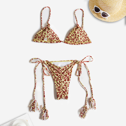 Black string bikini with wrap-around straps and gold-tone rings with tassels modeled on a beach. - Image 17