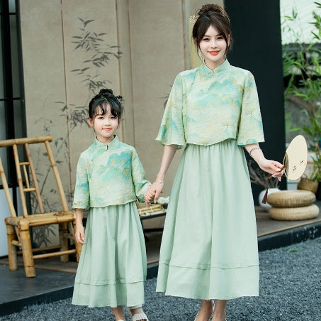 Mother and daughter in matching light green Chinese style cheongsam suits with patterned tops and solid skirts. - Image 14