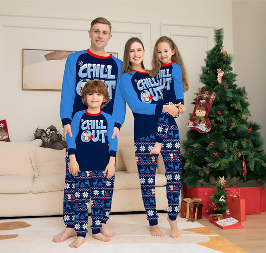 Family of four wearing matching blue and navy Christmas pajamas with 'CHILL OUT' snowman and snowflake patterns.