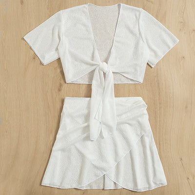 White two-piece swimwear set with a tie-front crop top and a high-waisted skirt with an asymmetrical ruffled hem. - Image 6