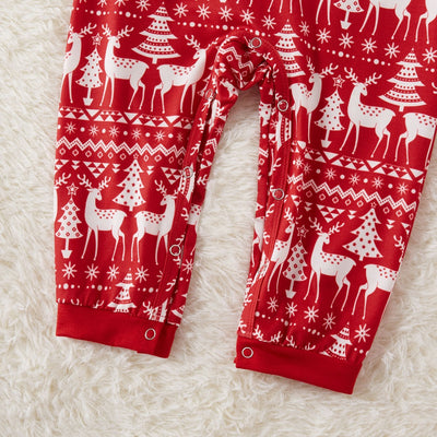 Family of four wearing matching red Christmas pajamas with white reindeer and tree patterns, standing by a decorated tree. - Image 4