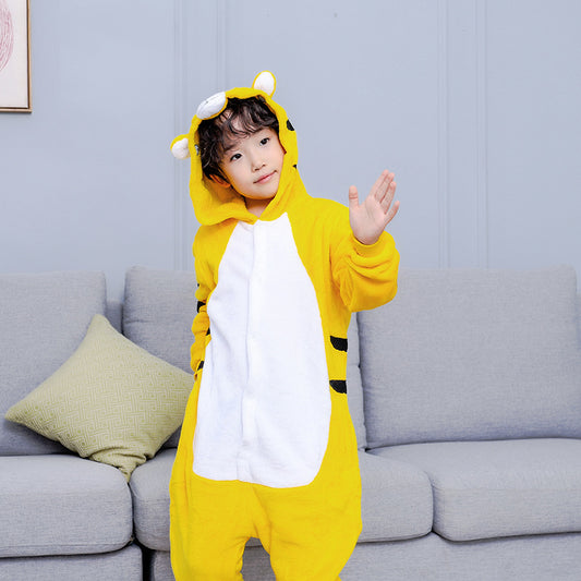 Young child in a yellow tiger hooded flannel pajama jumpsuit with white belly and black stripes, standing indoors.