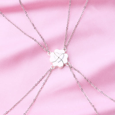 Four silver-colored necklaces, each with a half-heart charm that forms a four-leaf clover when combined, on pink satin. - Image 10