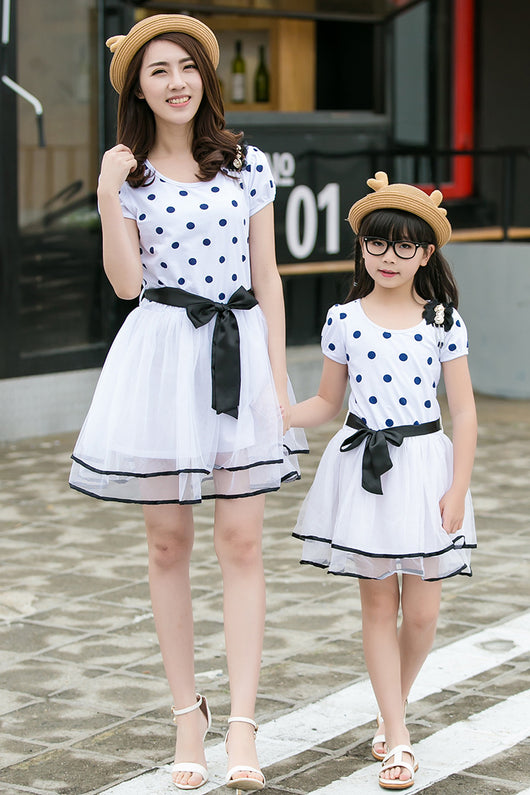 Family of four wearing matching white and black polka dot outfits. Dad and son in t-shirts, mom and daughter in dresses. - Image 12