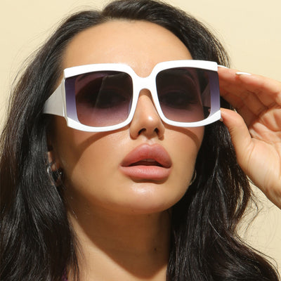 Oversized square-frame sunglasses with a light pink frame and gradient lenses transitioning from purple to orange to yellow.