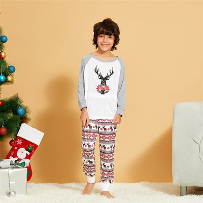 Young boy wearing a Christmas pajama set with a white and grey raglan top featuring a reindeer and fair isle print pants. - Image 2