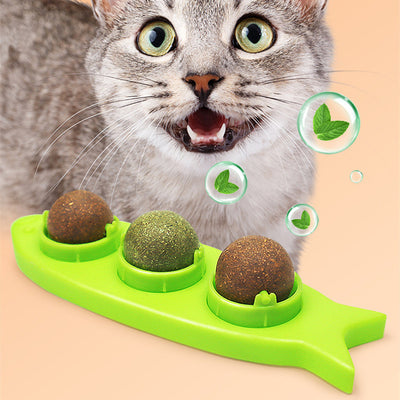 Pink fish-shaped cat molar stick toy with three compartments holding green and brown catnip or silvervine balls. Three clear plastic dome covers are shown.