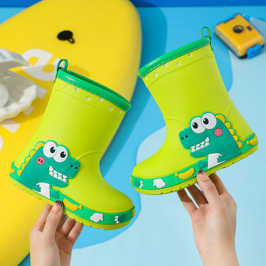 Bright yellow children's rain boots with a green cartoon dinosaur design and orange trim, held by hands. - Image 10
