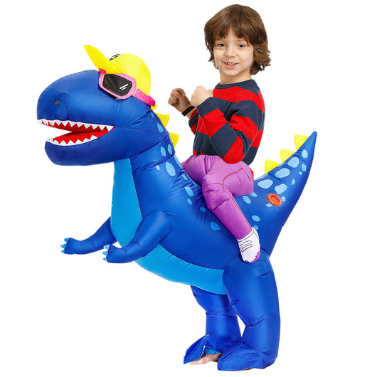 Young boy in an inflatable blue dinosaur costume with a yellow cap and pink goggles, next to a fan and battery pack.