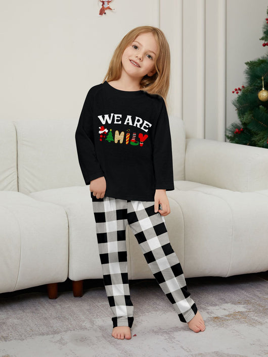 Family of four wearing matching black long-sleeve pajamas with "WE ARE FAMILY" text and black and white plaid bottoms. - Image 13