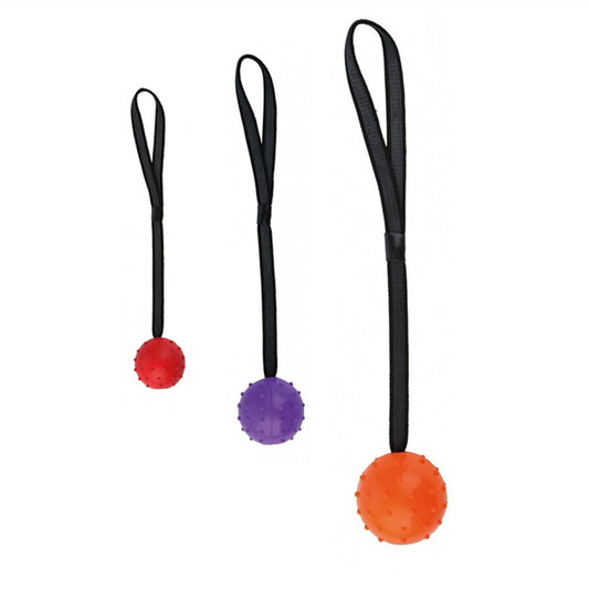 Red rubber dog training ball with nubs and a black rope handle, designed for bite resistance and molar cleaning.
