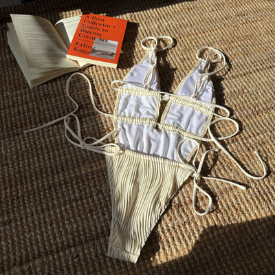 Woman in a light yellow ribbed one-piece tie-front backless bikini relaxing on a sandy beach by the ocean. - Image 12