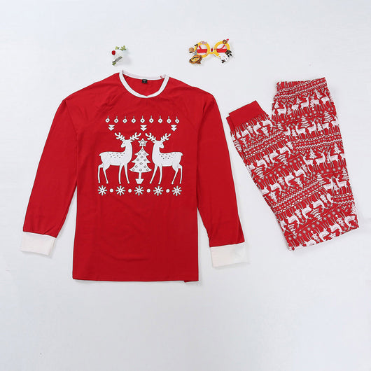 Red long-sleeve Christmas pajama set with white reindeer and Christmas tree patterns, featuring a crew neck top and patterned pants.