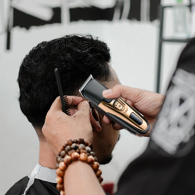 Gold and black three-in-one electric shaver with foil head, hair clipper, nose trimmer, and accessories.