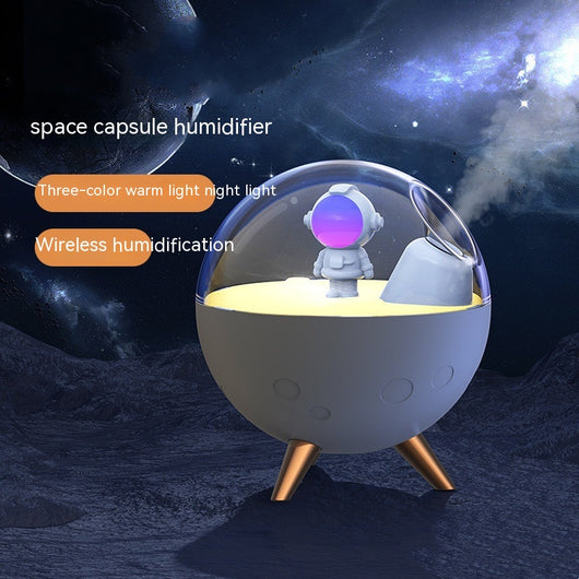 Space gray spaceman humidifier with a clear dome, glowing purple astronaut figurine, and warm yellow night light.